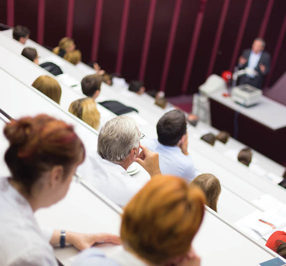 Lecturer at university  Healthcare expert giving a talk to medical faculty professors  Participants listening to lecture and making notes 
